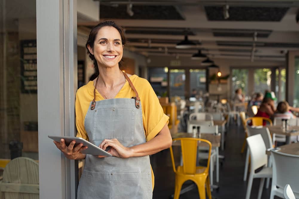 woman business owner with tablet smiling, representing franchises under 200k