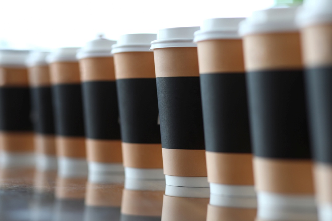 Line of paper cups standing at table, representing coffee franchise opportunities