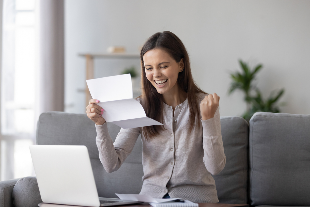 Woman Smiling at Approved Loan Paper - Unsecured Loan Criteria & The Unsecured Loan Process