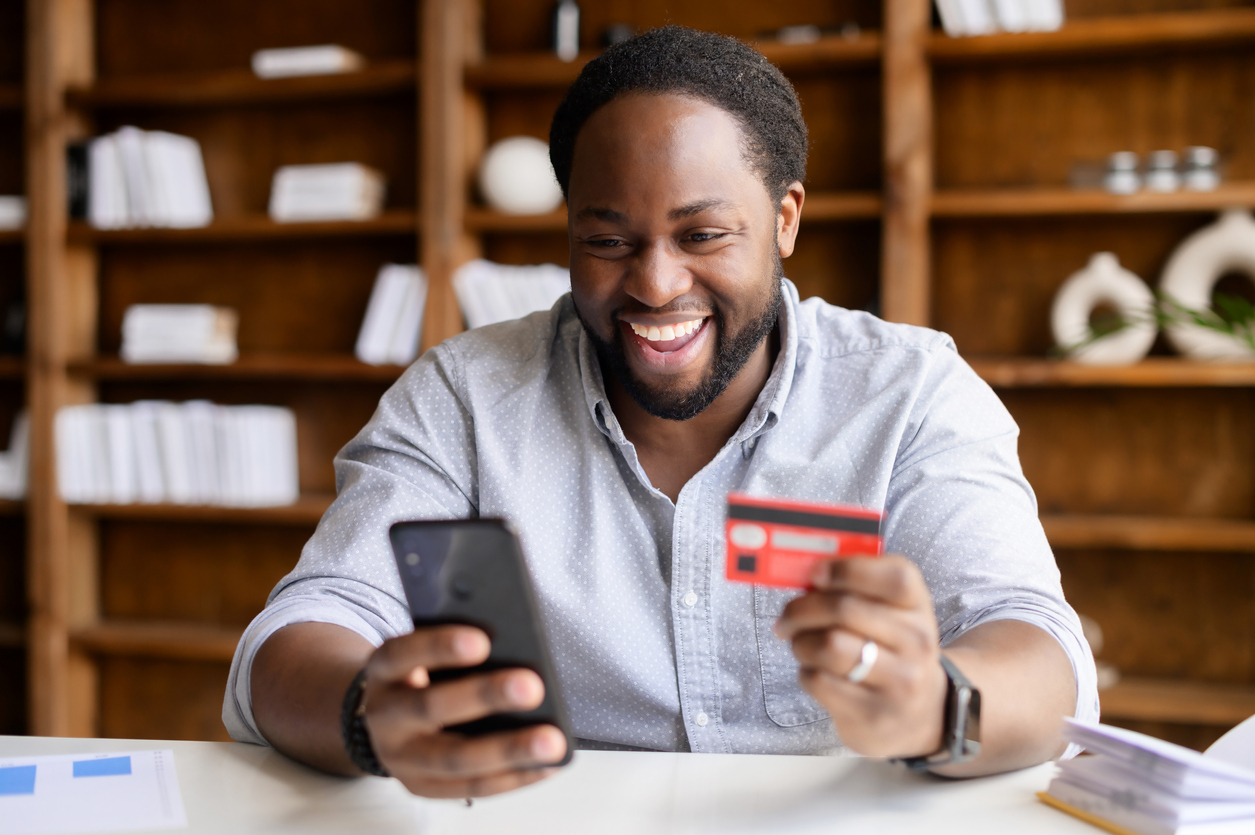 Man Smiling at Phone & Credit Card - What Does Credit Card Utilization Have to Do With My Credit Score?