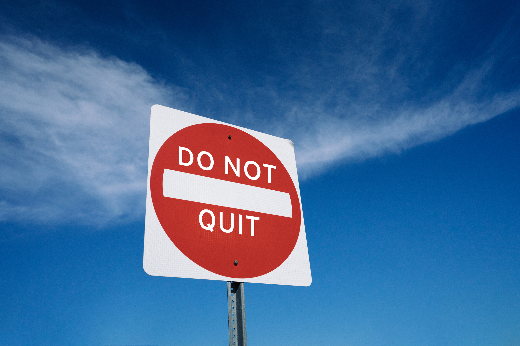 "Do Not Quit" sign against blue sky