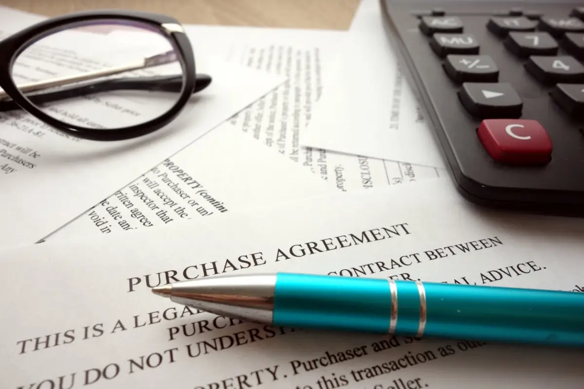 A purchase agreement with a pen on it, representing financing a business purchase